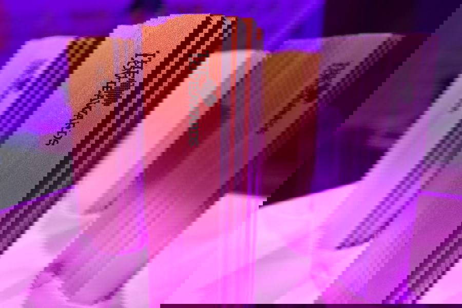 Four metallic trophies with The Love Awards logo stand upright on a pink-lit surface, reminiscent of Lovie Awards elegance. The trophies feature a modern, ridged design and vary in colour tones, set against a purple background.