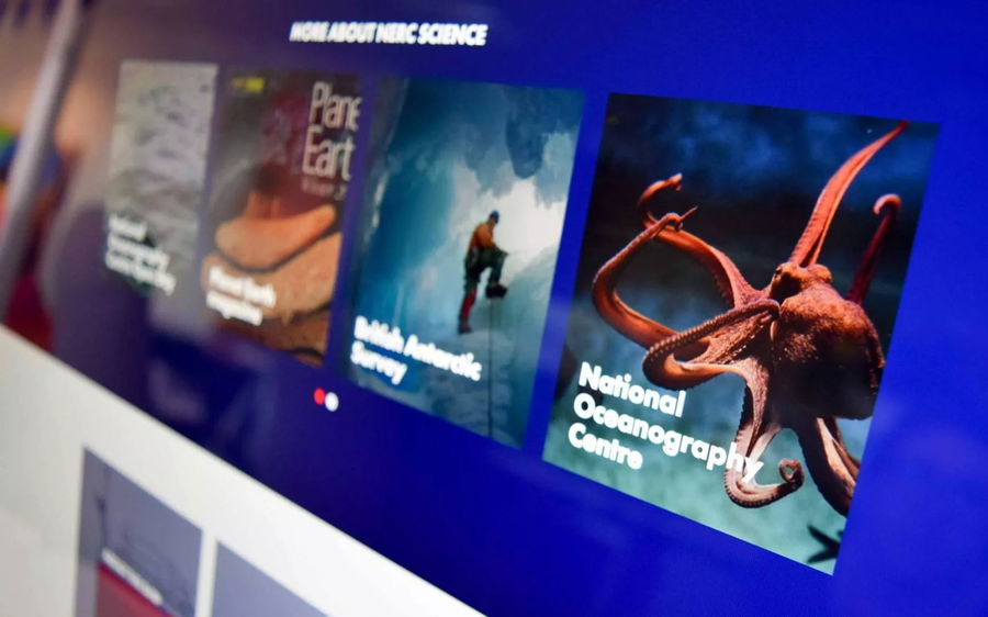 Close-up of a computer screen displaying a website section with science-related tiles, including images and titles about oceans, surveys, Planet Earth, and the National Oceanography Centre featuring an octopus image.