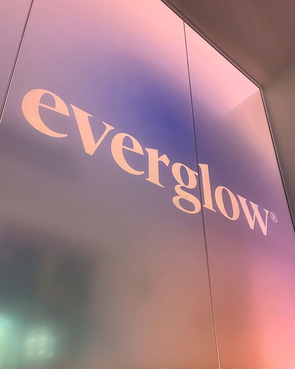 A wall with a gradient of soft pink, purple, and blue stag colours displays the word everglow in large, white, lowercase letters.